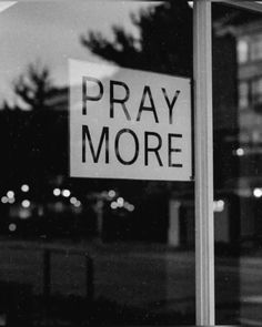 a black and white photo of a sign that says pray more on the front window