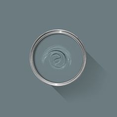 a can of paint with a long shadow on the wall next to it's lid