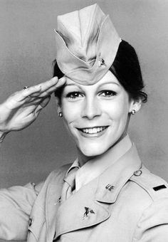 a black and white photo of a woman in uniform saluting with her hat on