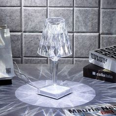 a clear lamp sitting on top of a table next to some books and a phone