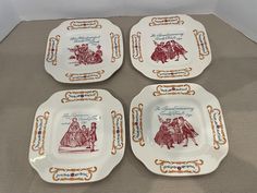 four porcelain plates with designs on them sitting on a cloth covered tableclothed surface