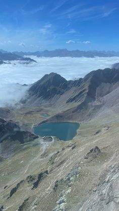 an aerial view of mountains and lakes in the distance, with low lying clouds surrounding them