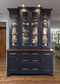 a blue china cabinet with glass doors and gold handles in a large open kitchen area