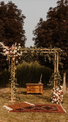 an outdoor ceremony setup with flowers and greenery on the ground, in front of trees