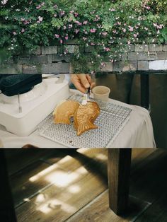 a person pouring something into a cup on top of a table with flowers in the background