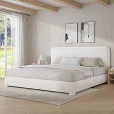 a white bed sitting in a bedroom on top of a hard wood floor next to a window