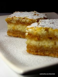 two pieces of cake sitting on top of a white plate covered in powdered sugar