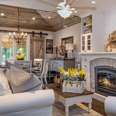 a living room filled with furniture and a fire place in front of a fireplace under a wooden ceiling