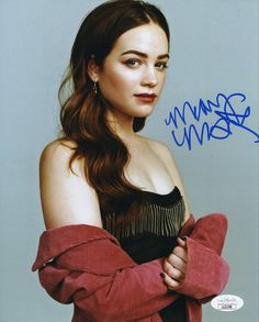 an autographed photo of a woman with long brown hair and wearing red gloves