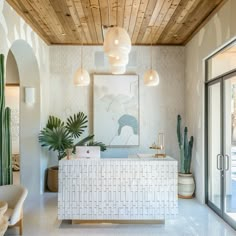 a white reception table in the middle of a room with potted cacti