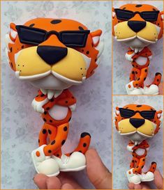 an orange and black animal with sunglasses on it's face is being held up