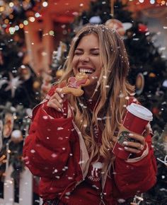 a woman eating a donut and drinking coffee in front of a christmas tree