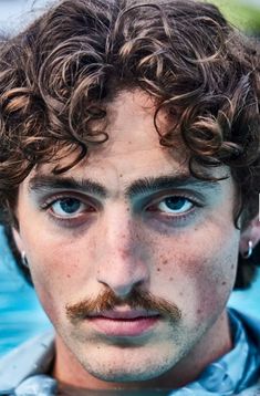 a man with curly hair and a moustache on his face