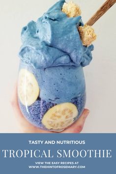 a person holding up a blue smoothie with banana slices in it and the text tropical blue smoothie parfait jar