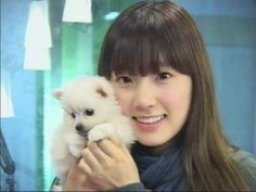 a woman holding a small white dog in her hands