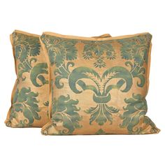 two pillows with green and gold designs on them, one in the shape of a fleur