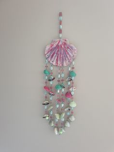 a pink shell hanging from the side of a wall next to beads and other items