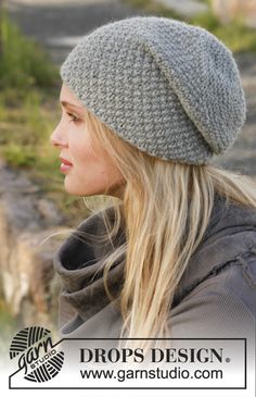 a woman wearing a gray knitted hat with long blonde hair, looking off to the side