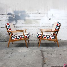 two chairs sitting next to each other in front of a wall