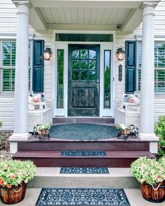 a front porch with two planters on the steps and an entry way leading up to it