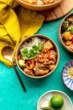 three bowls filled with rice, meat and veggies on top of a blue table