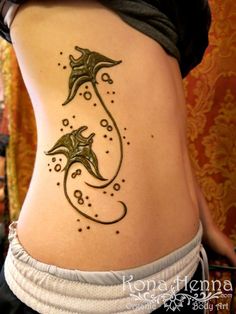 a woman with a tattoo on her stomach that has two dolphins in the middle of it