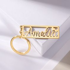 a gold keychain with the word amelie on it sitting on a white surface