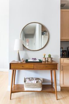 a wooden table with a mirror on the wall above it and a basket underneath it