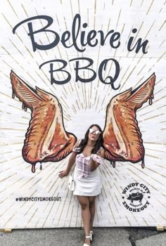 a woman standing in front of a sign that says believe in bbq