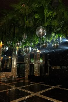 disco ball chandeliers hanging from the ceiling in an indoor area with black and white marble flooring