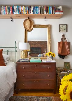 a bedroom with a bed, dresser and bookshelf filled with lots of books