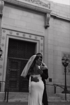 a man and woman are standing in front of a building with a veil on their head