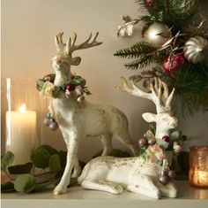 two deer figurines sitting next to each other on a shelf with christmas decorations