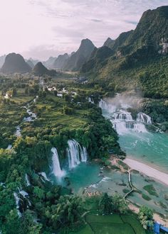 an aerial view of a waterfall in the middle of a river surrounded by lush green mountains