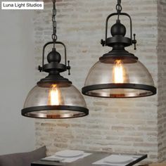 two lights hanging over a table in front of a brick wall