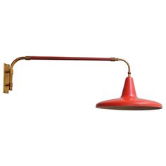 a red wall mounted light with a long arm and an orange cone shade on it