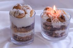 two small glass containers filled with food on top of a white cloth covered tablecloth