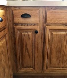 a kitchen with wooden cabinets and a white sink under a faucet mounted on a wall