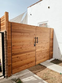 a large wooden gate is next to a white house