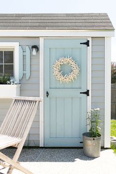 a blue shed with a wreath on the door and a lawn chair in front of it