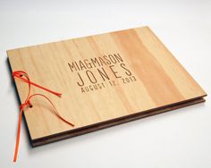 a wooden wedding guest book with sunglasses on it and an orange string attached to the cover