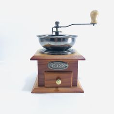 an old fashioned coffee grinder with a wooden base and metal bowl on the top