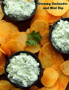 four small black bowls filled with creamy corianade and mint dip surrounded by tortilla chips