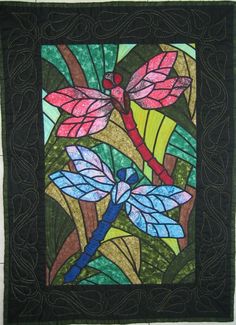 a quilted wall hanging with dragonflies on it