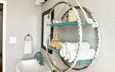 a bathroom with a sink, mirror and hanging shelf filled with white towels on top of it