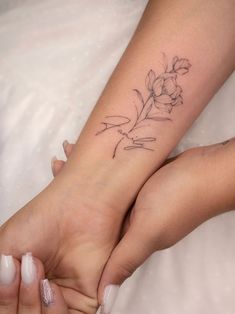 two people holding hands with tattoos on their arms and one has a flower tattooed on the wrist