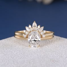 an oval shaped diamond ring on top of a white cloth with a flower motif in the center