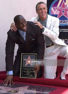 two men in suits and one is holding up a star on the hollywood walk of fame