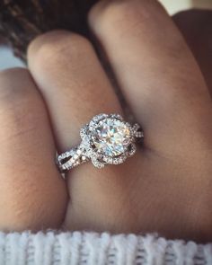 a close up of a person's hand with a diamond ring on their finger