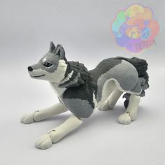 a gray and white wolf figurine sitting on the ground